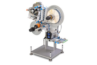 Eine Etikettiermaschine mit mehreren Rollen, die Etiketten auf Produkte aufbringt. Sie verfügt über verschiedene mechanische Komponenten und eine stabile Basis.