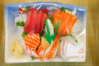 Ein Sushi-Set mit verschiedenen Sorten, darunter Lachs, Thunfisch und Garnelen, auf einem Teller mit Beilagen wie Ingwer und Gemüse.