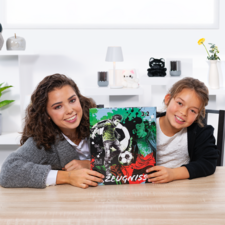 Zwei Mädchen halten ein Fußball-Zeugnis mit einer Grafik und der Punktzahl 3:2. Sie sitzen an einem Tisch in einem hellen Raum.