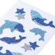 Glitzernde Aufkleber von Delfinen und Sternen in verschiedenen Blautönen auf einem weißen Hintergrund.