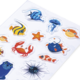 Bunte Aufkleber mit verschiedenen Meereslebewesen, darunter Fische, Krabben, Seesterne und eine Qualle auf einem weißen Hintergrund.