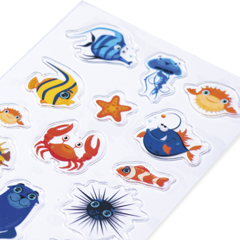 Bunte Aufkleber mit verschiedenen Meereslebewesen, darunter Fische, Krabben, Seesterne und eine Qualle auf einem weißen Hintergrund.
