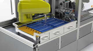 Automatisierte Laborvorrichtung mit einem gelben Roboterarm, der eine blaue und eine gelbe Ablage für Proben oder Materialien bearbeitet.