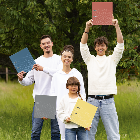 Vier Personen stehen im Freien und halten jeweils einen Ordner in verschiedenen Farben. Sie tragen helle Kleidung und lächeln.