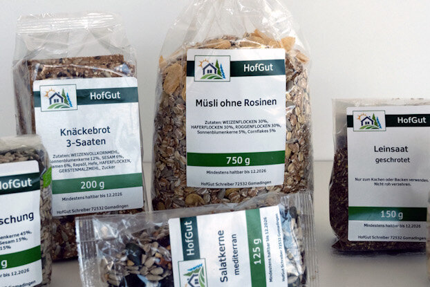 Rollenetiketten im Digitaldruck online bestellen: Tüten mit verschiedenen Saaten und Nüssen, mit digital gedruckten Etiketten, auf einem Tisch angeordnet.