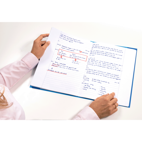 Eine Person hält ein aufgeschlagenes Heft mit handschriftlichen Notizen und Markierungen in blauer und roter Tinte.