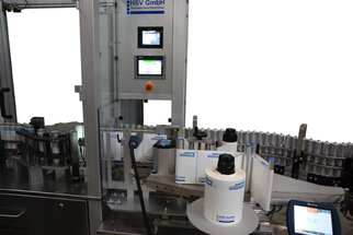 Automatische Etikettiermaschine mit mehreren Rollen, Steuerungseinheit und Etiketten auf Flaschen.