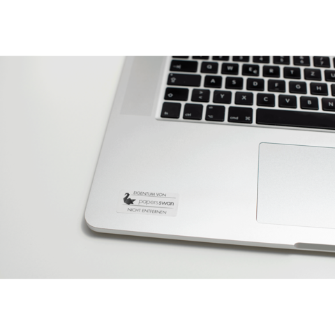Ein Laptop mit einer Tastatur und einem Aufkleber, der "EIGENTUM VON paperswan NICHT ENTFERNEN" zeigt.