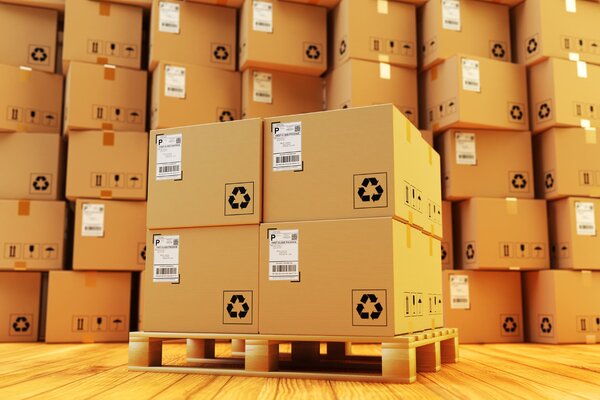 Stapelhaufen von Kartons auf einer Palette, mit Recycling-Symbolen und Adressetiketten sichtbar.