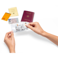 Eine Hand hält eine transparente Hülle mit einer ID-Karte, umgeben von verschiedenen Ausweisdokumenten, darunter ein Reisepass und mehrere Karten.
