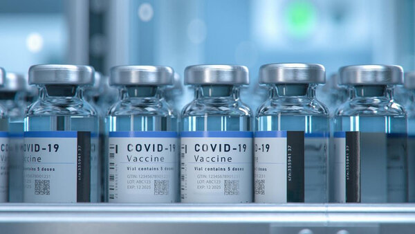 COVID-19-Impfstofffläschchen in einer Reihe, jedes mit einem Etikett, das die Inhaltsstoffe und Dosierung angibt.