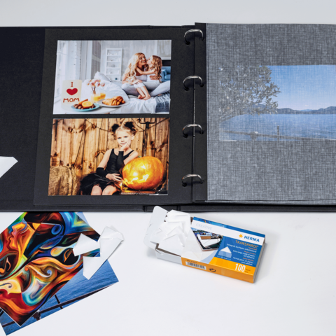 Ein Fotoalbum mit mehreren Bildern, darunter Porträts und Landschaften, sowie einige lose Fotokarten und eine Filmverpackung.