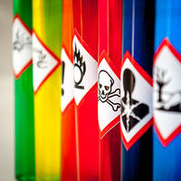 Gefahrgutetiketten auf farbigen Behältern in der Chemiebranche