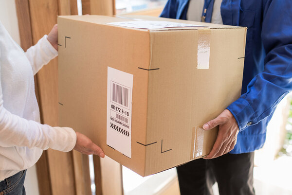 Versand- und Palettenetiketten: Paketauslieferung an der Haustür, Mann übergibt Paket mit Versandetikett